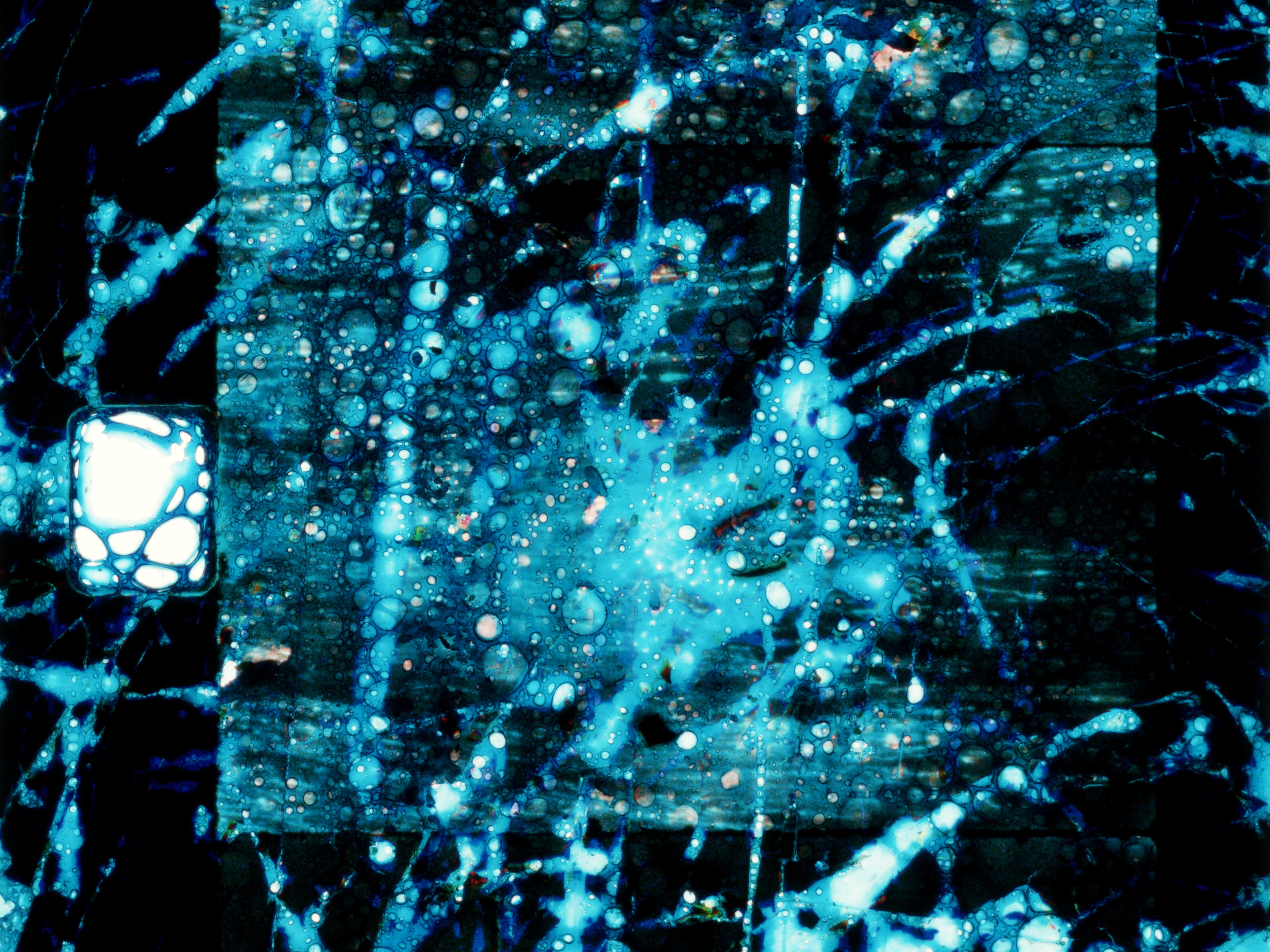 A vibrant abstract pattern with blue hues, featuring splattered and bubble-like textures on a dark background.